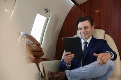 Photo of Businessman working on tablet in airplane during flight