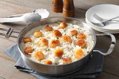 Photo of Delicious scallop pasta served on wooden table