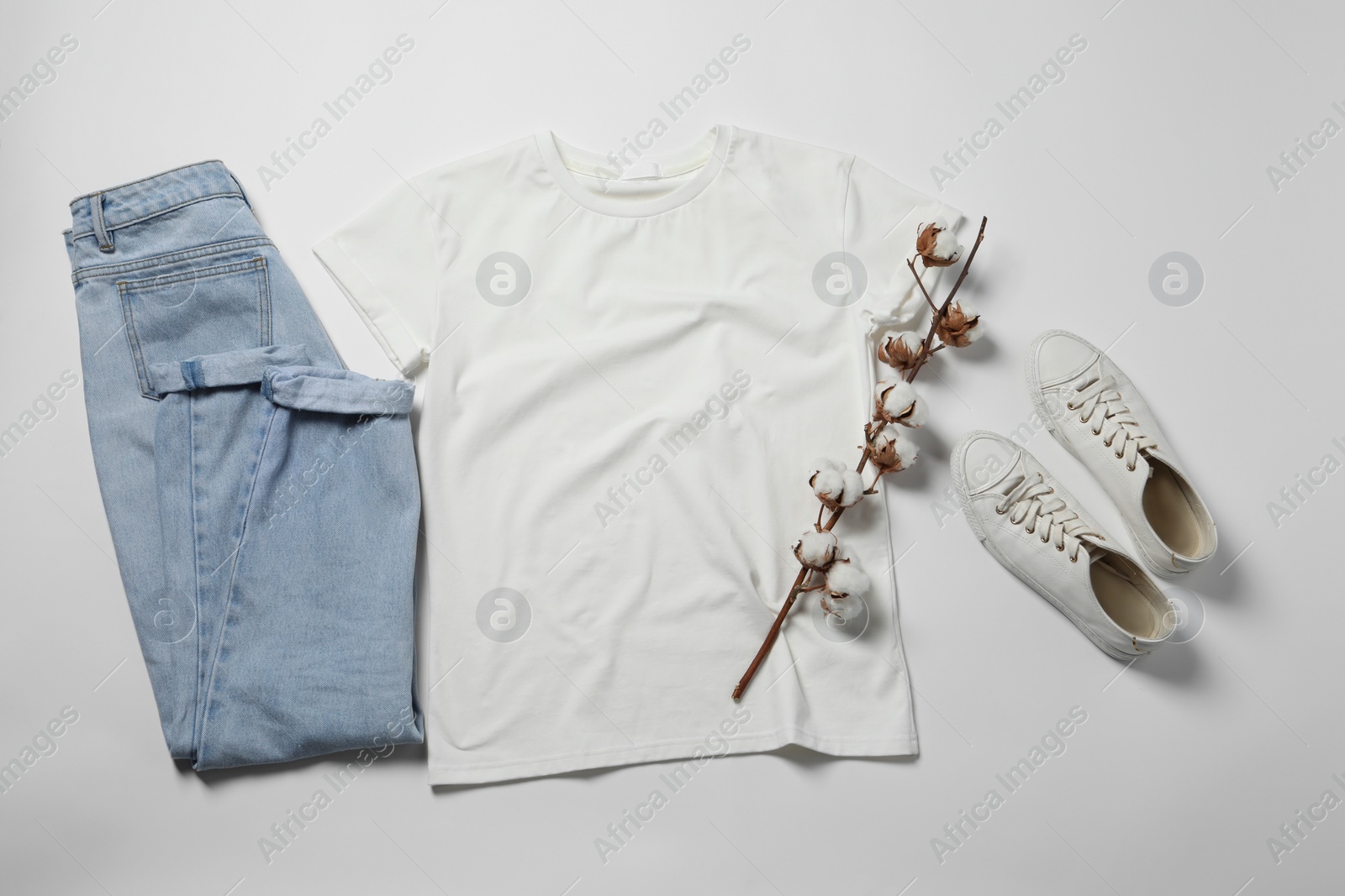 Photo of Stylish t-shirt, jeans and sneakers on white background, flat lay