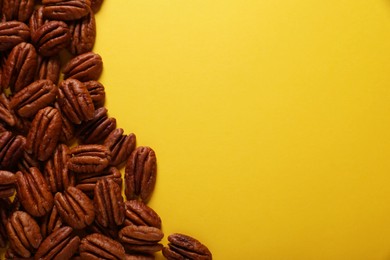 Photo of Tasty pecan nuts on yellow background, flat lay. Space for text