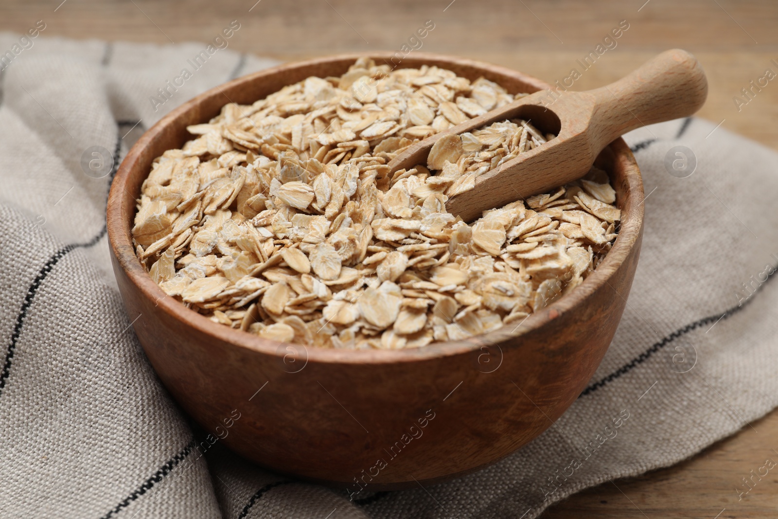 Photo of Bowl and scoop with oatmeal on wooden table, closeup