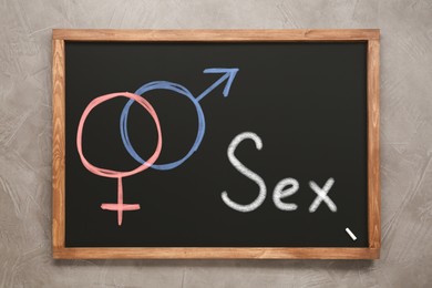 Image of Sexual education. Small black chalkboard with word Sex, female and male gender signs on grey background, top view
