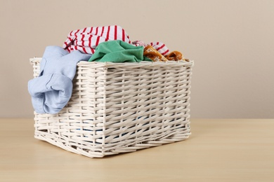 Wicker laundry basket with different clothes on wooden table