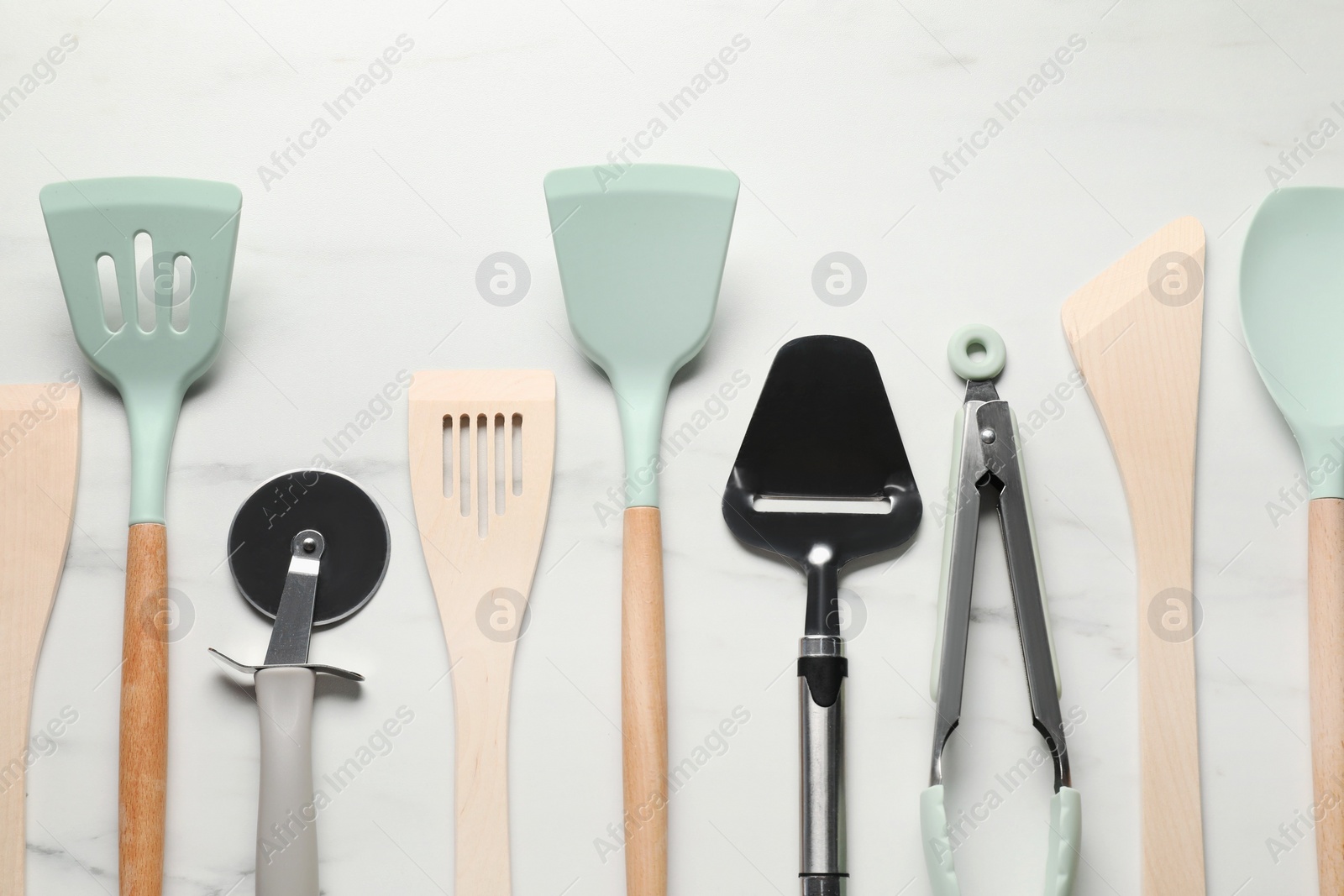 Photo of Different spatulas and other kitchen utensils on white marble table, flat lay