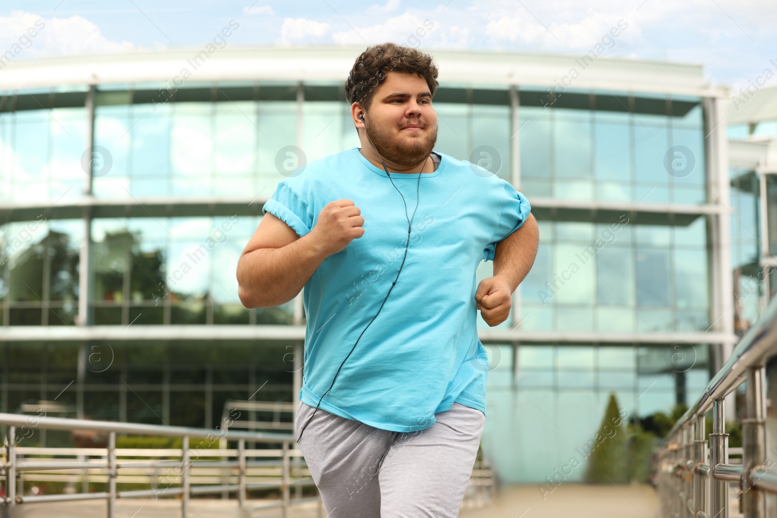 Photo of Young overweight man running outdoors. Fitness lifestyle