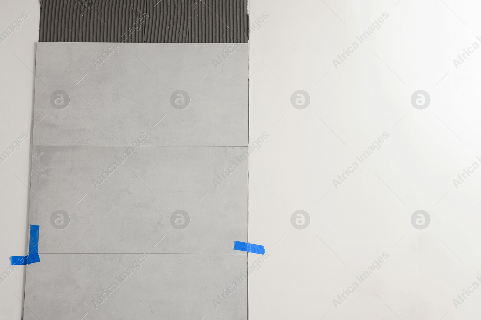 Photo of Adhesive mix with tiles on white wall