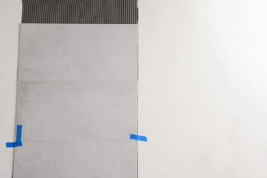 Photo of Adhesive mix with tiles on white wall