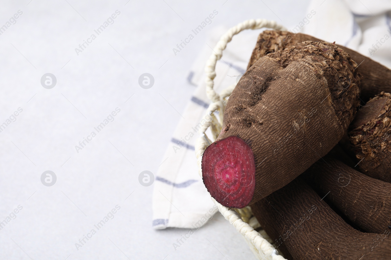 Photo of Whole and cut red beets in basket on white table, closeup. Space for text