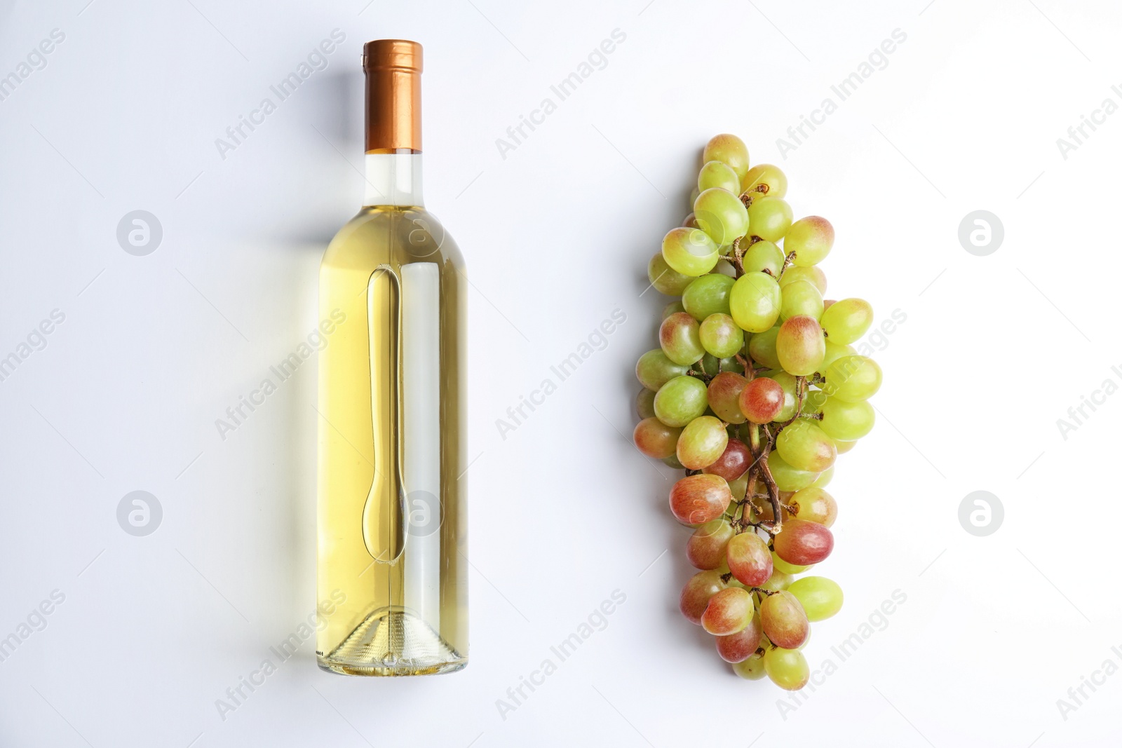 Photo of Fresh ripe juicy grapes and bottle of wine on white background, top view