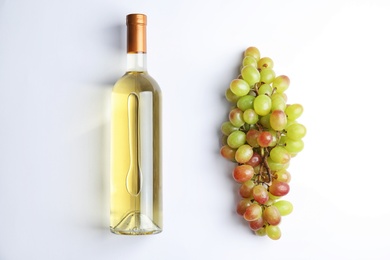 Photo of Fresh ripe juicy grapes and bottle of wine on white background, top view