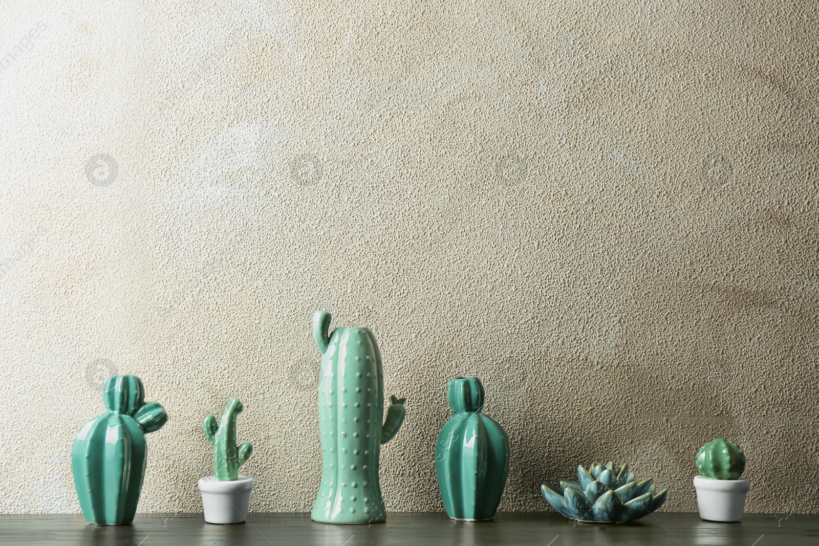 Photo of Decorative cacti on table near color wall, space for text. Interior decor