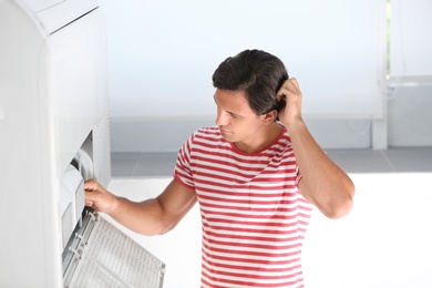 Photo of Young man fixing air conditioner at home