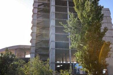 Unfinished building and green trees outdoors on sunny day