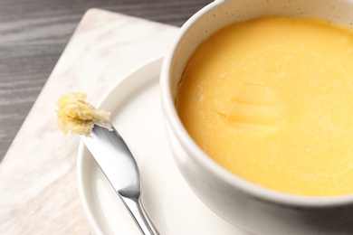 Bowl and knife with melting butter on table, closeup. Space for text