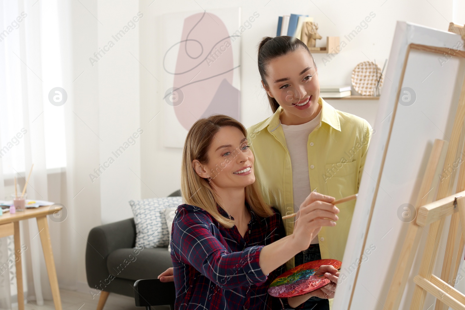 Photo of Artist teaching her student to paint in studio. Creative hobby