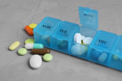 Weekly pill box with medicaments on grey table, closeup
