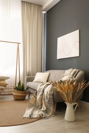 Photo of Vase with dry plants on floor in living room. Interior design