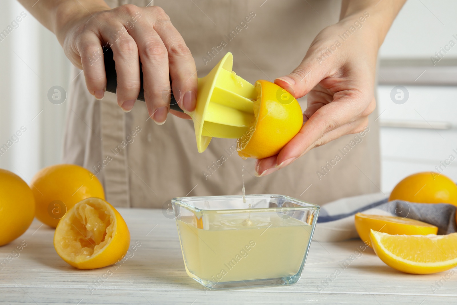 Photo of Woman squeezing lemon juice with reamer at table, closeup