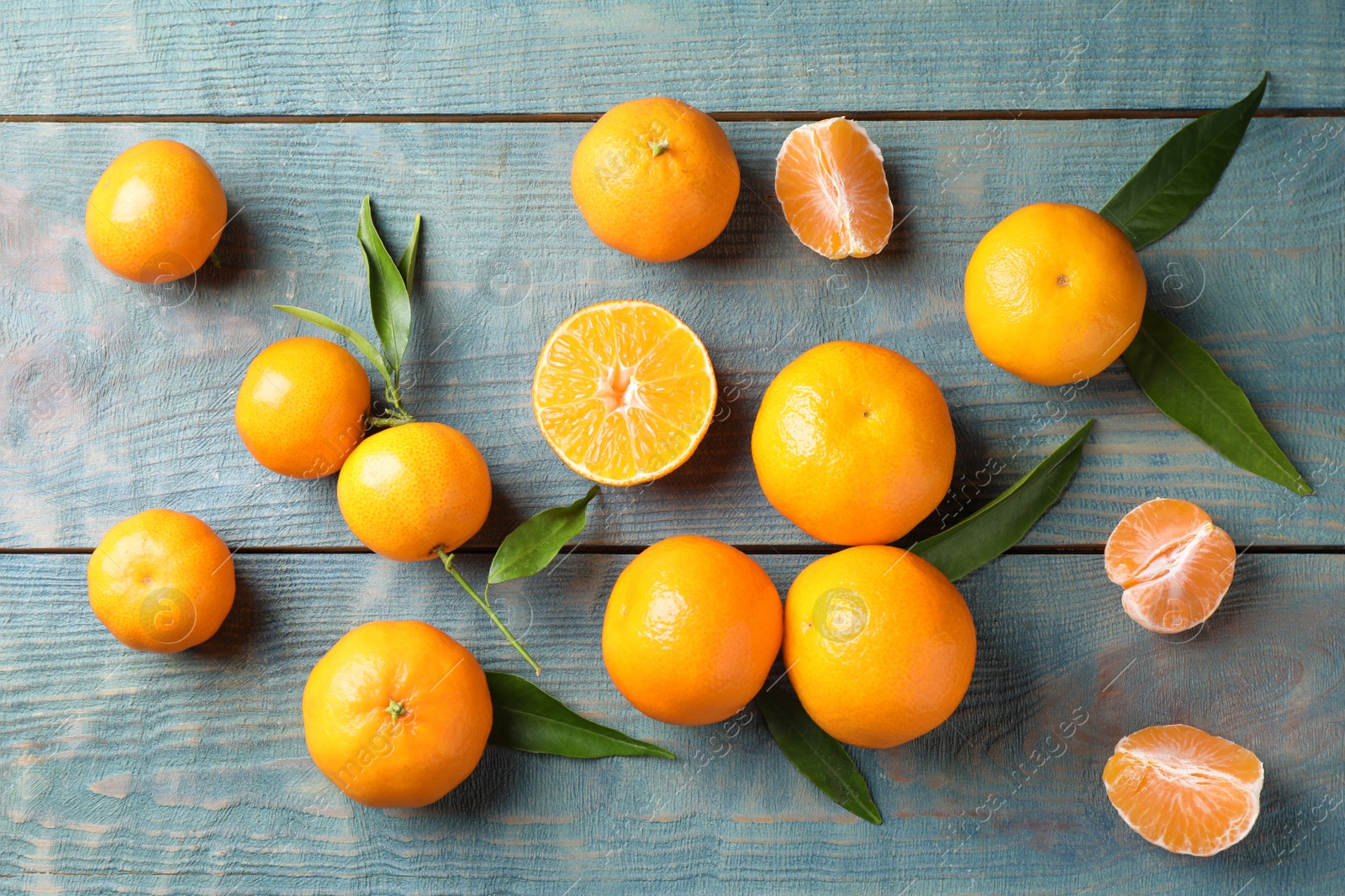Photo of Fresh ripe tangerines on blue wooden table, flat lay