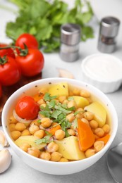 Photo of Tasty chickpea soup in bowl served on light grey table