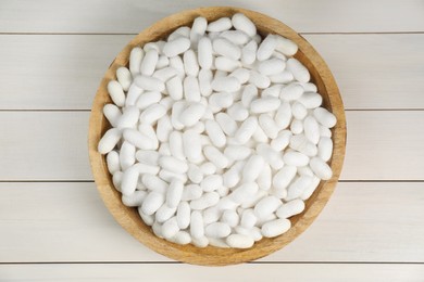 Silk cocoons in bowl on white wooden table, top view