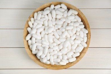 Photo of Silk cocoons in bowl on white wooden table, top view