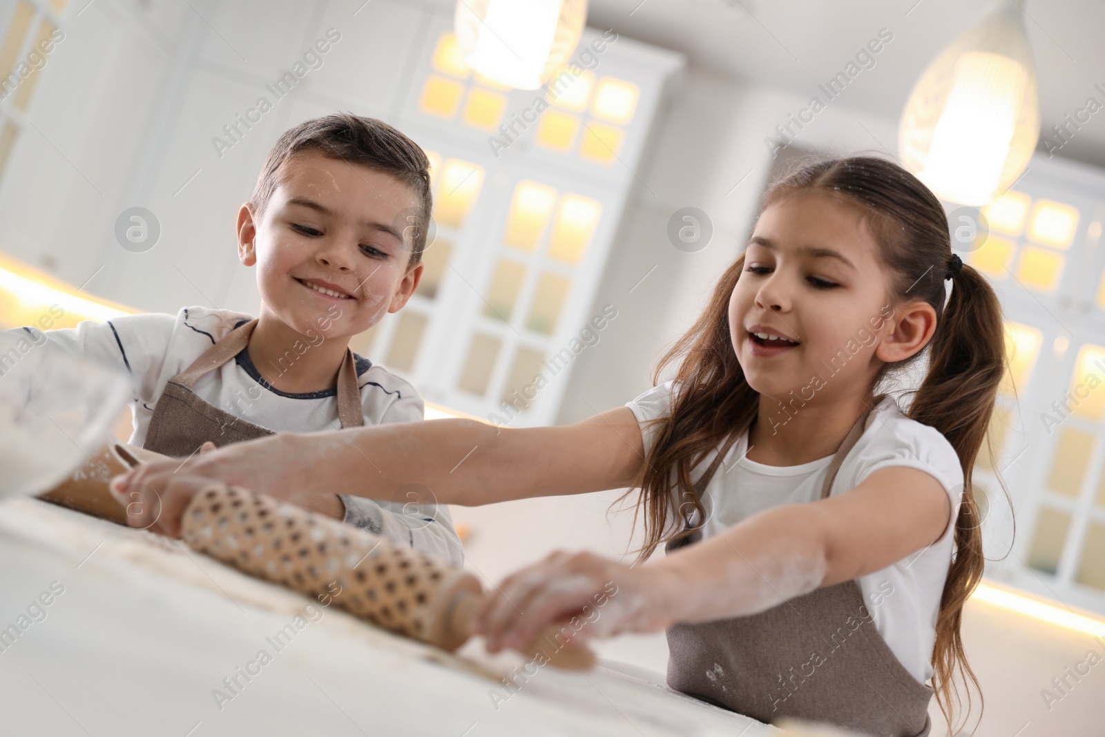 Photo of Cute little children cooking dough together in kitchen