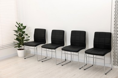 Photo of Many chairs near white wall in waiting area indoors