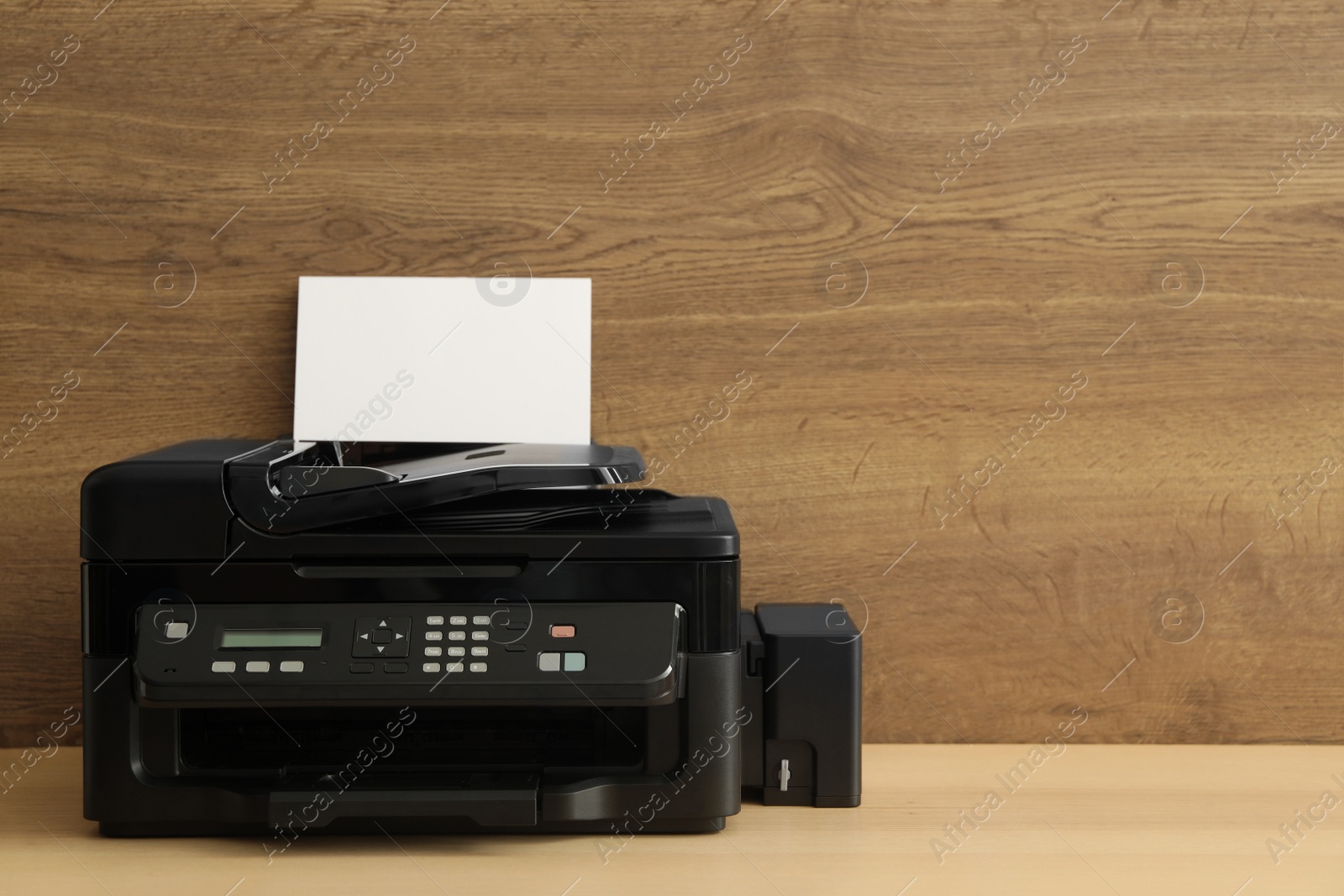 Photo of Modern printer with paper on wooden table. Space for text