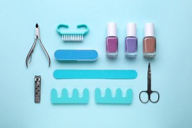 Set of pedicure tools on light blue background, flat lay