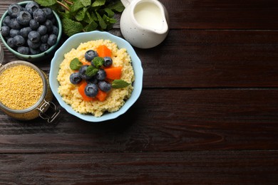 Photo of Tasty millet porridge with blueberries, pumpkin and mint in bowl on wooden table, flat lay. Space for text