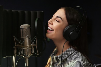 Photo of Young singer with microphone recording song in studio