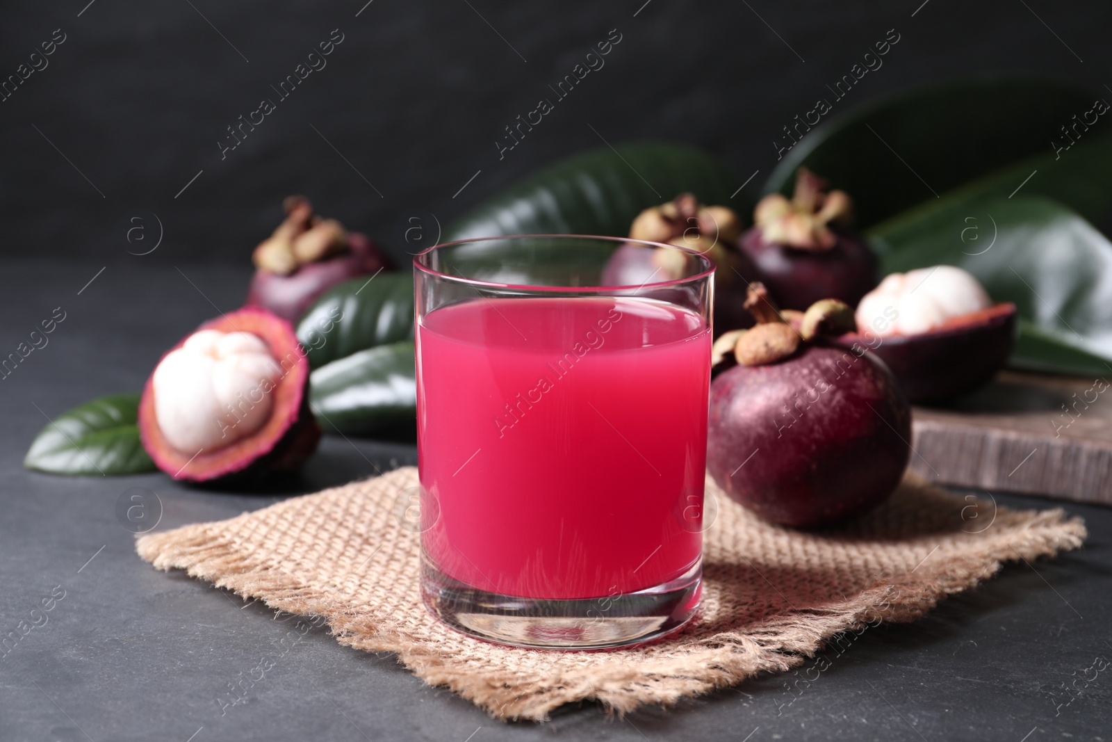Photo of Delicious fresh mangosteen juice in glass on dark table