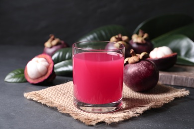Delicious fresh mangosteen juice in glass on dark table