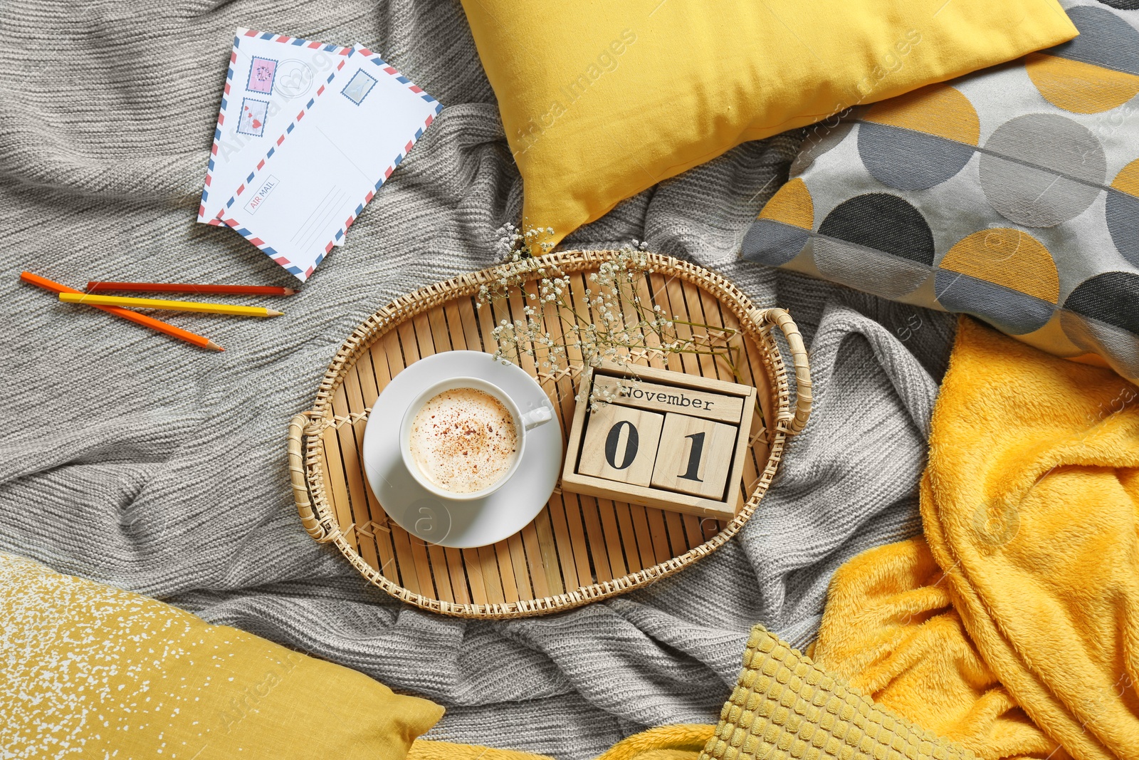 Photo of Flat lay composition with cup of coffee, wooden block calendar, pillows and plaid on bed