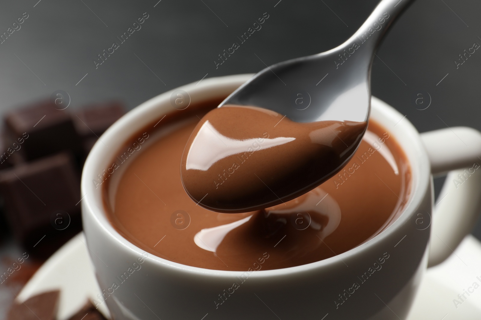 Photo of Spoon with yummy hot chocolate over cup, closeup