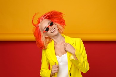 Beautiful young woman with bright dyed hair shaking head on color background