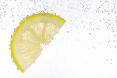 Photo of Juicy lemon slice in soda water against white background, closeup. Space for text