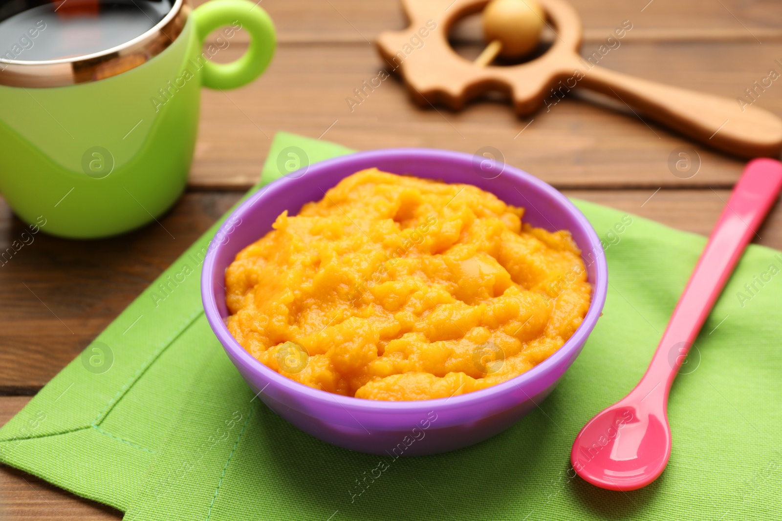 Photo of Plastic dishware with healthy baby food on wooden table, closeup