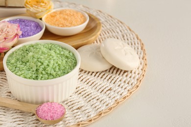 Bowls with different sea salt, soap bars and rose on light grey table. Space for text