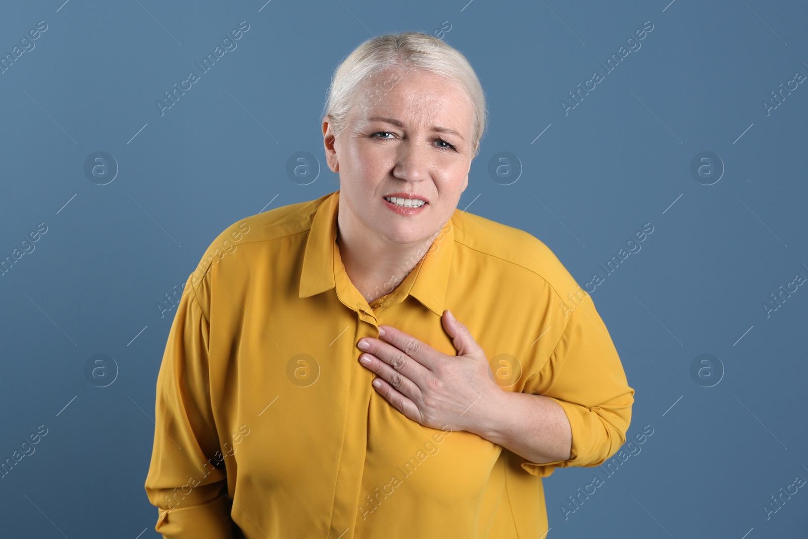 Photo of Mature woman having heart attack on color background