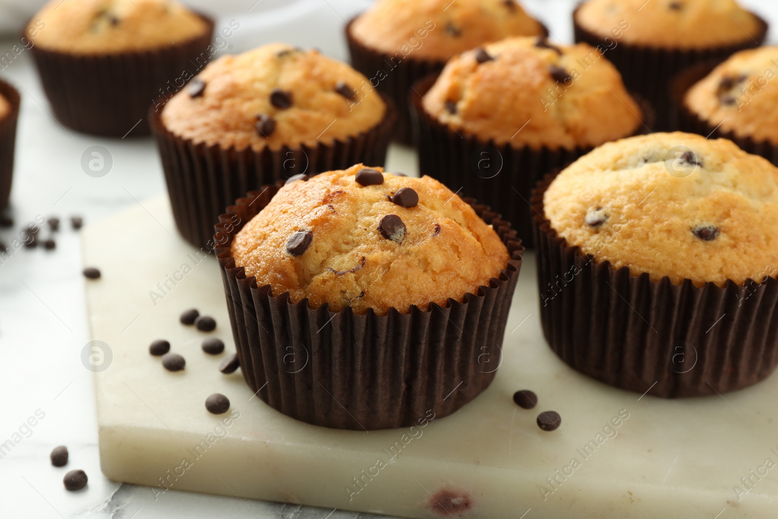 Photo of Delicious sweet muffins with chocolate chips on table, closeup