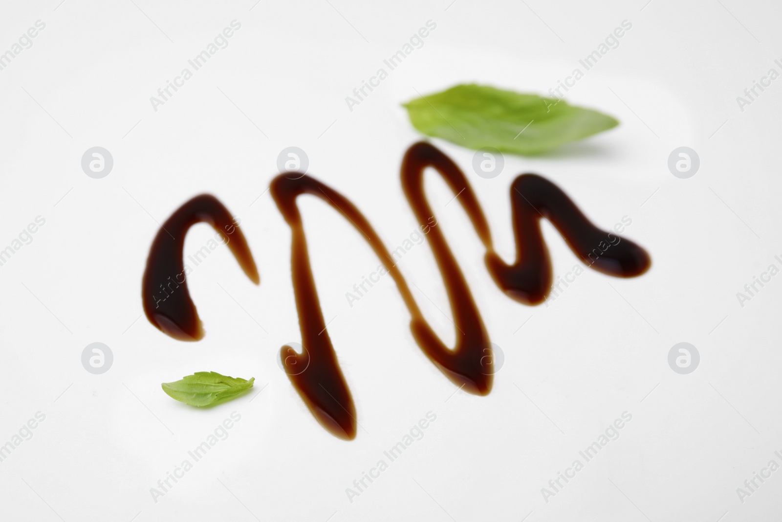 Photo of Organic balsamic vinegar and basil leaves on white background