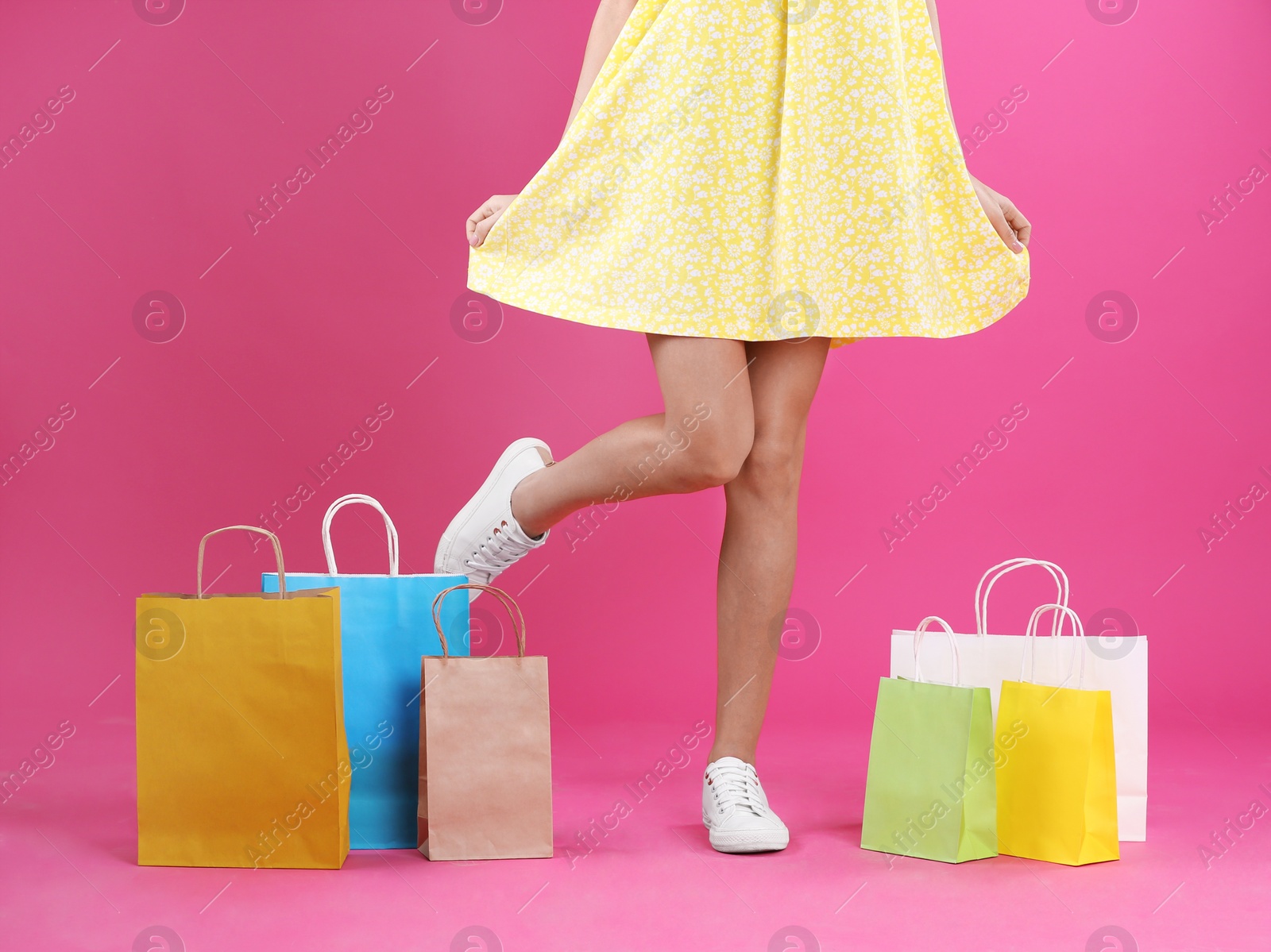 Photo of Young woman with shopping bags on color background, closeup