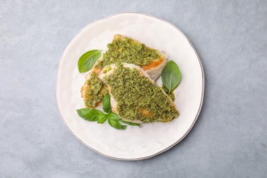 Photo of Delicious chicken breasts with pesto sauce and basil on light gray table, top view
