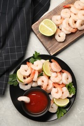 Photo of Tasty boiled shrimps with cocktail sauce, parsley and lime on light grey table, flat lay