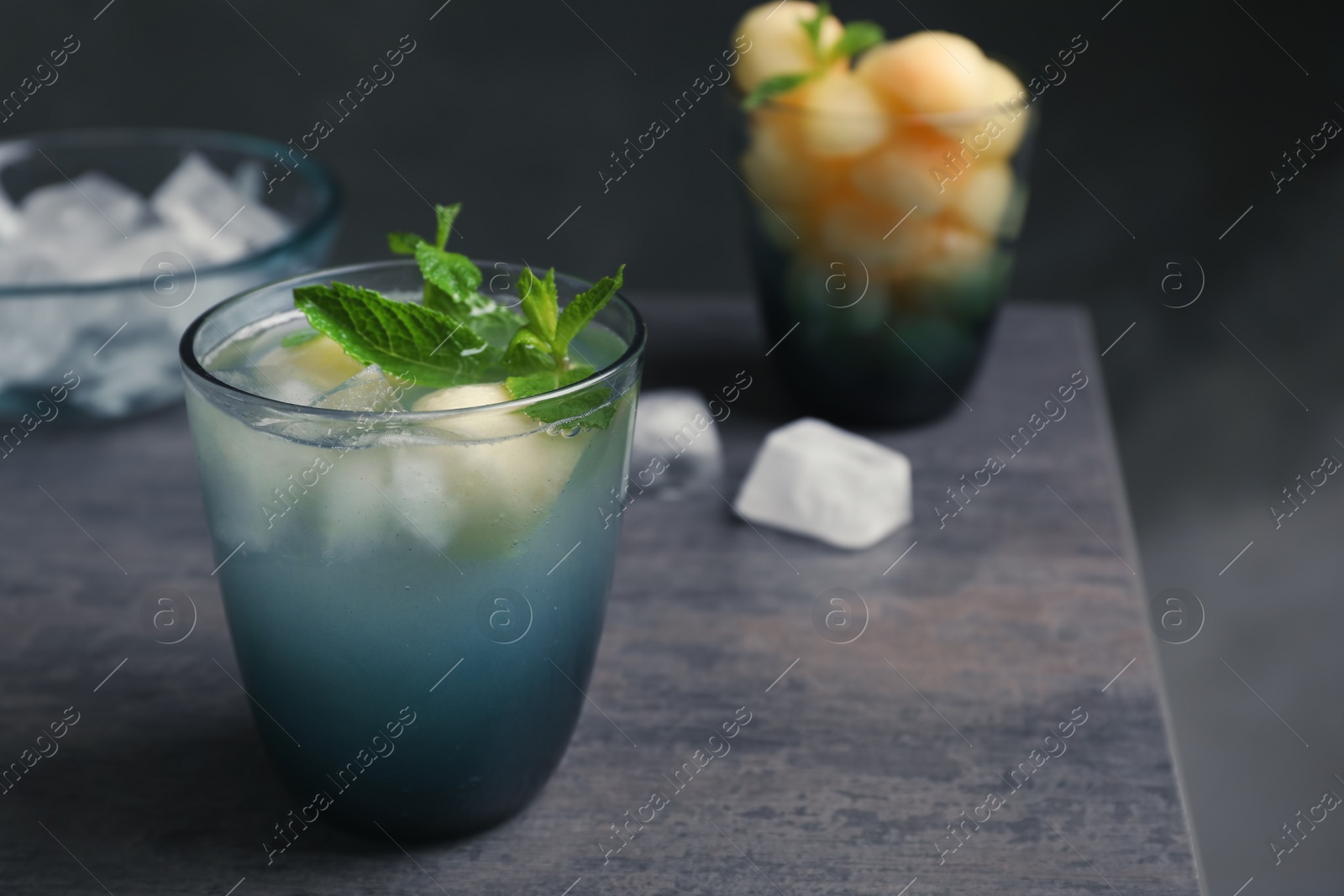 Photo of Glass with tasty melon ball drink on table against dark background. Space for text