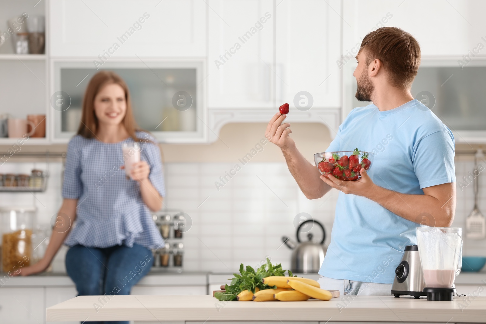 Photo of Young couple preparing delicious milk shake in kitchen