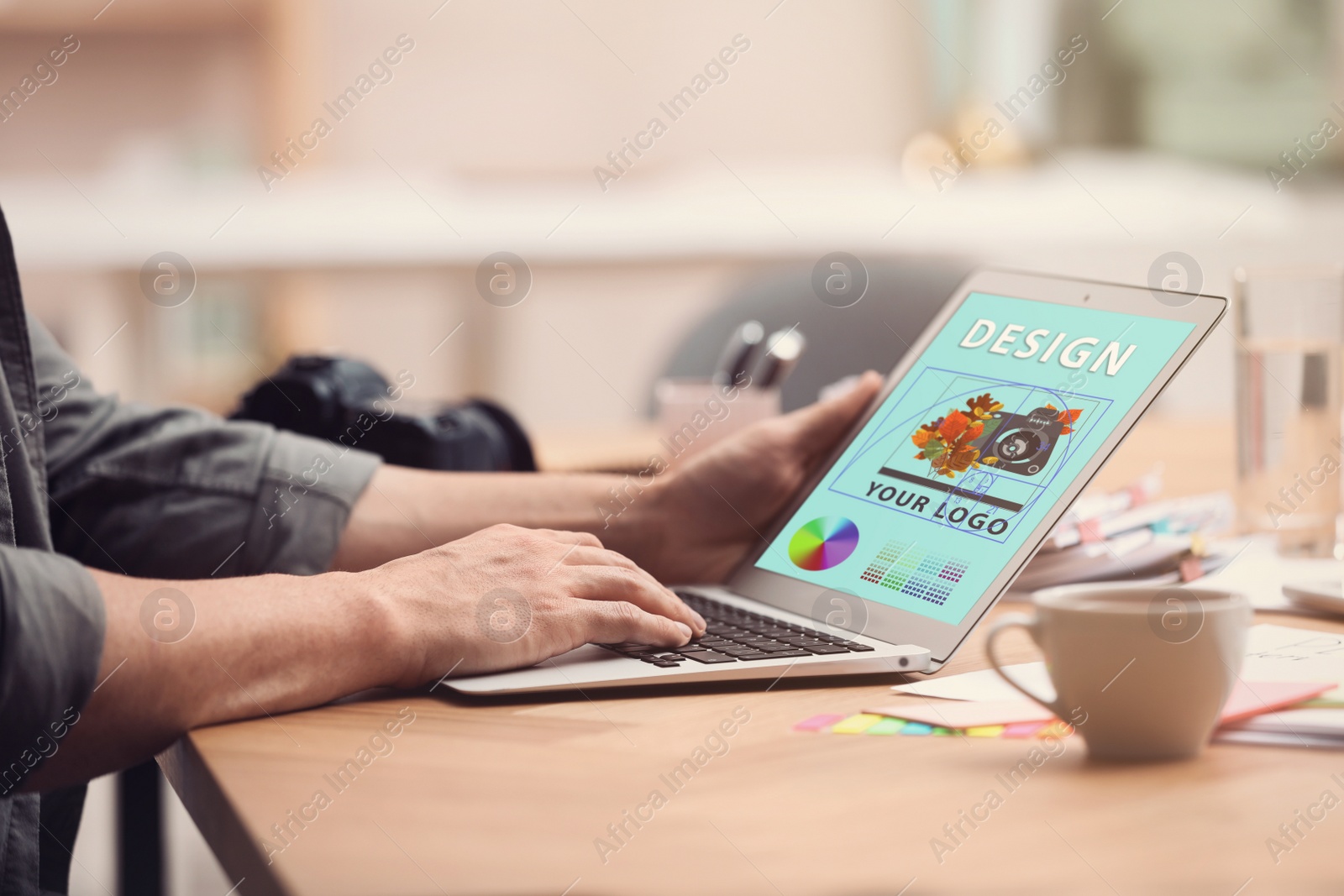 Image of Professional male designer working with laptop at desk in modern office, closeup 