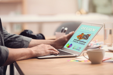 Professional male designer working with laptop at desk in modern office, closeup 